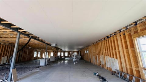 Drywall ceiling boarded across a large open new build near Moose Jaw, with the walls framed and a ladder set up mid-room
